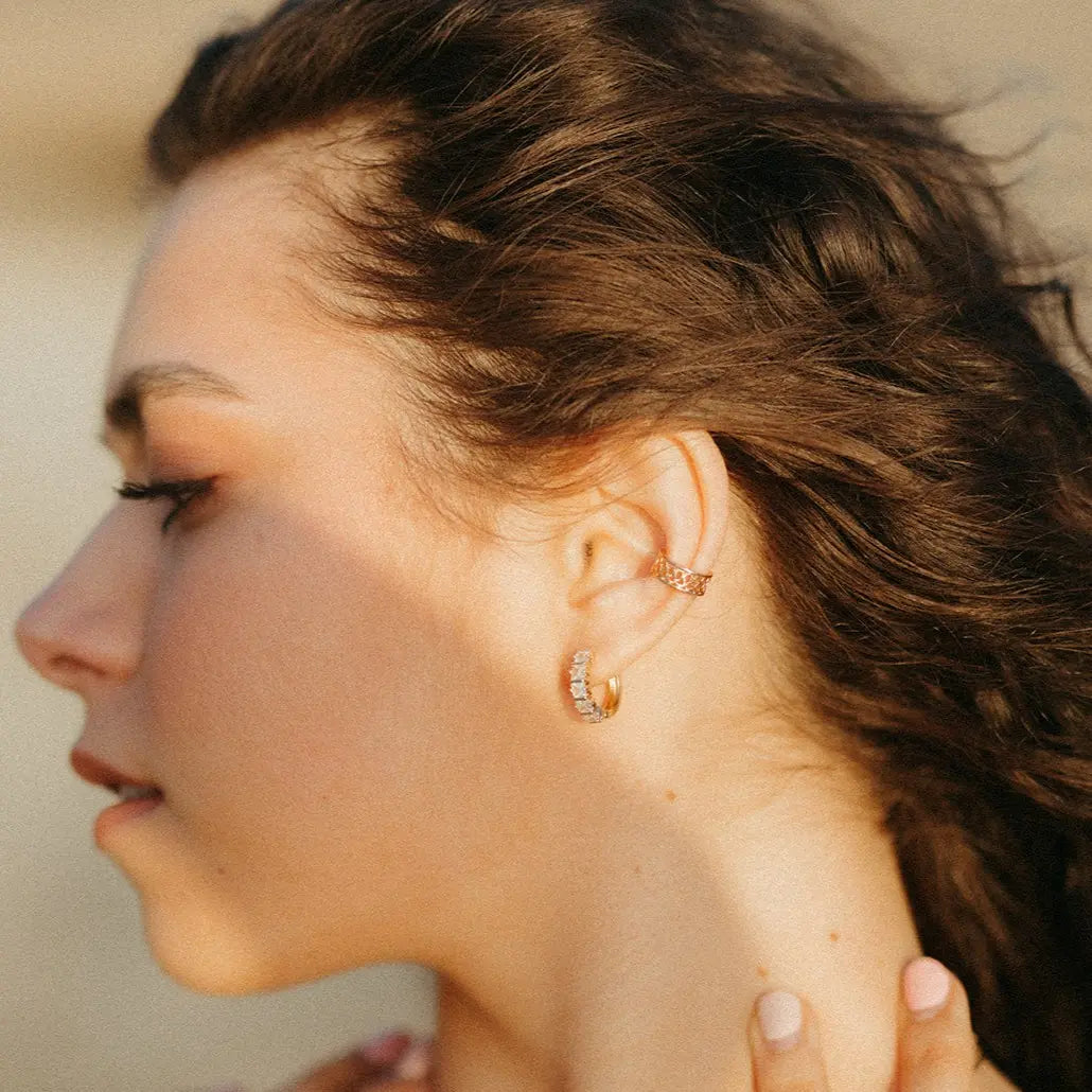 Close-up of a woman wearing gold earrings with a neutral background