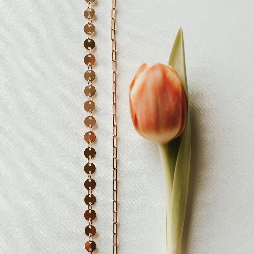Rose gold chain necklace with a single tulip on a light background