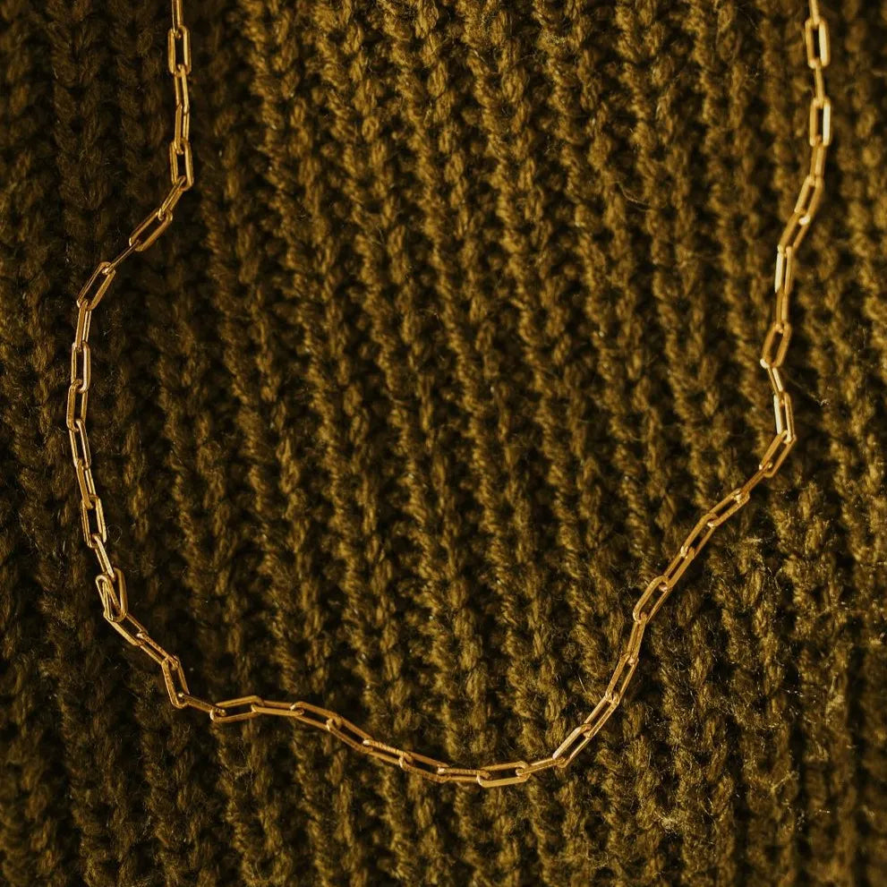 Gold chain necklace on a textured brown fabric background