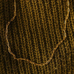 Gold chain necklace on a textured brown fabric background