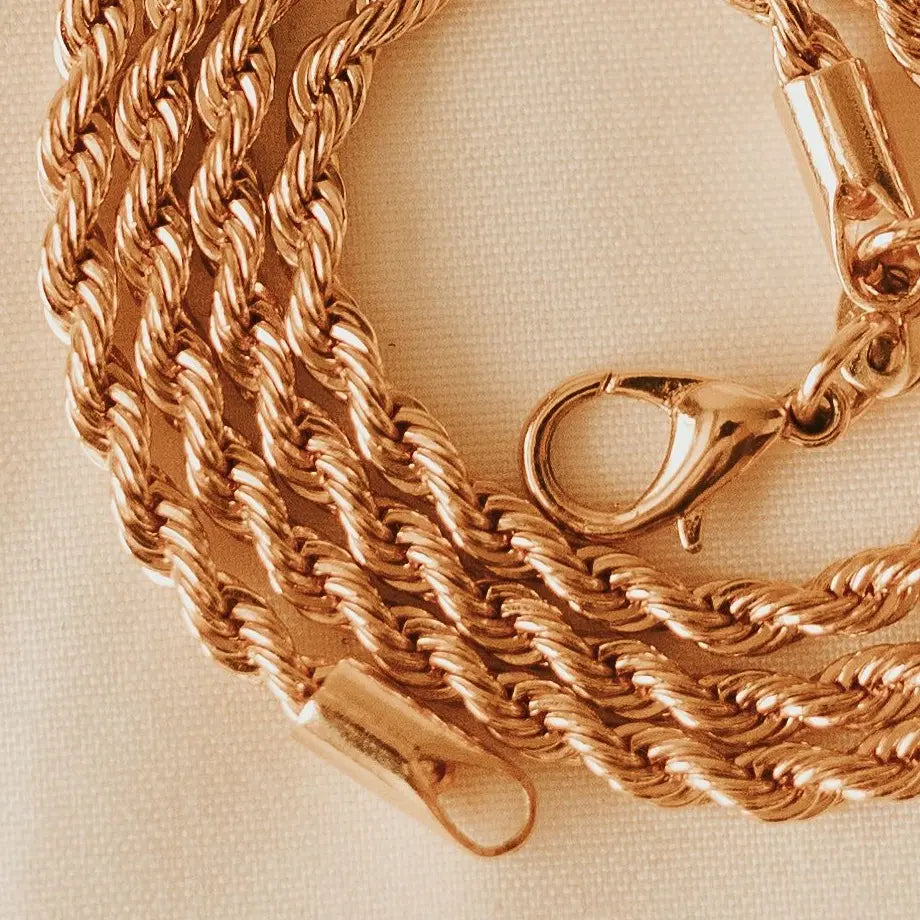 gold rope chain necklace on a beige background