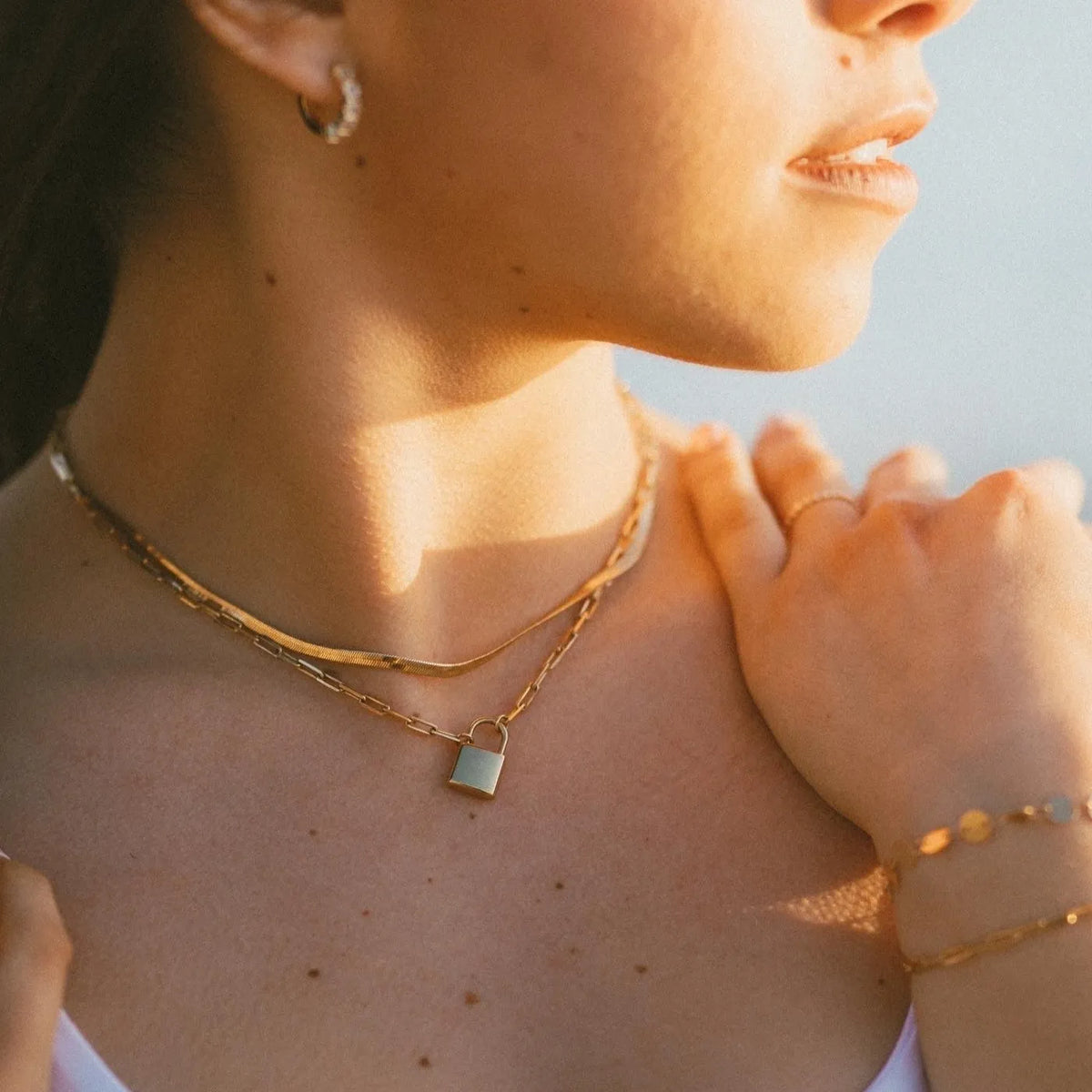 Close-up of a person wearing gold necklaces and bracelets with a blurred background