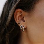 Close-up of an ear wearing two hoop earrings with a neutral background