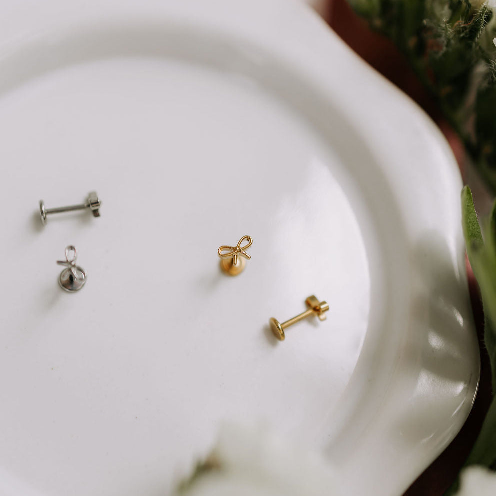 Three pairs of earrings on a white plate with a blurred floral background