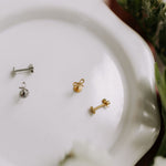 Three pairs of earrings on a white plate with a blurred floral background