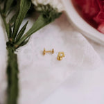 Gold flower-shaped earrings on a white cloth with a blurred background