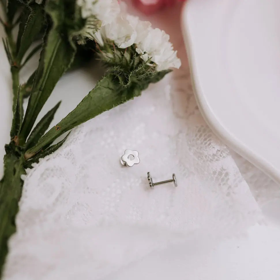 Silver earrings on a white lace doily with greenery