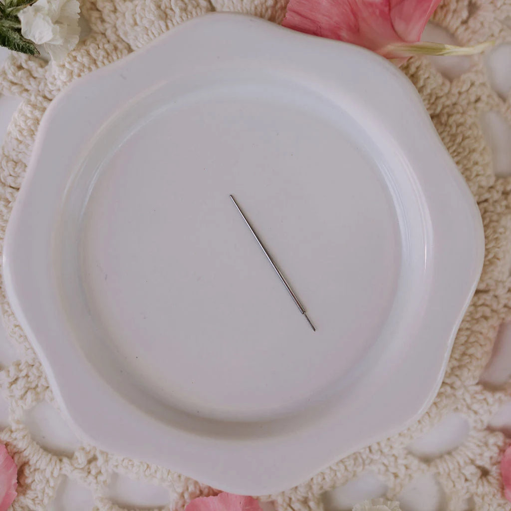 White plate with a flat back applicator on a textured surface with flowers