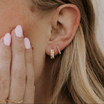 Close-up of an ear wearing gold hoop earrings with a blurred background