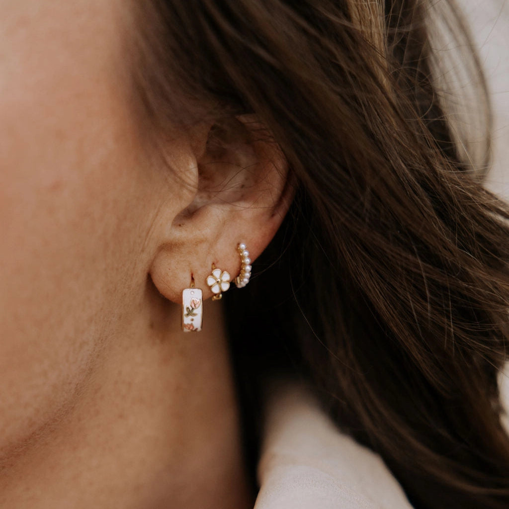 Close-up of an ear wearing two gold hoop earrings with small stones.