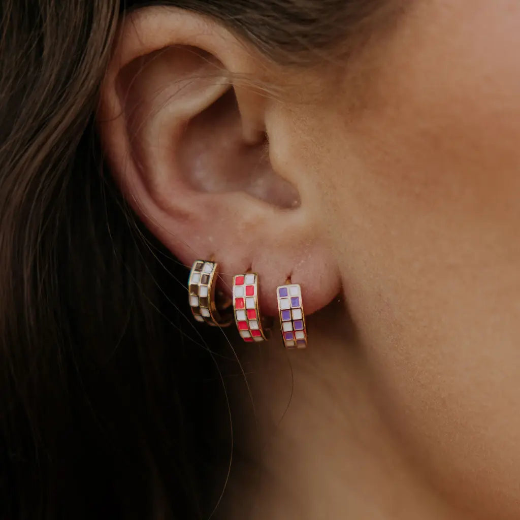 Close-up of an ear wearing colorful checkered hoop earrings.