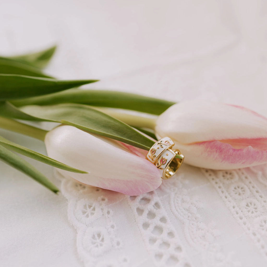 Gold earring on pink tulips with a white lace doily