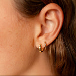 Close-up of a person wearing a gold hoop earring.