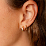 Close-up of a person wearing a gold hoop earring.