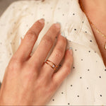 Close-up of a hand wearing two gold rings on a blurred background