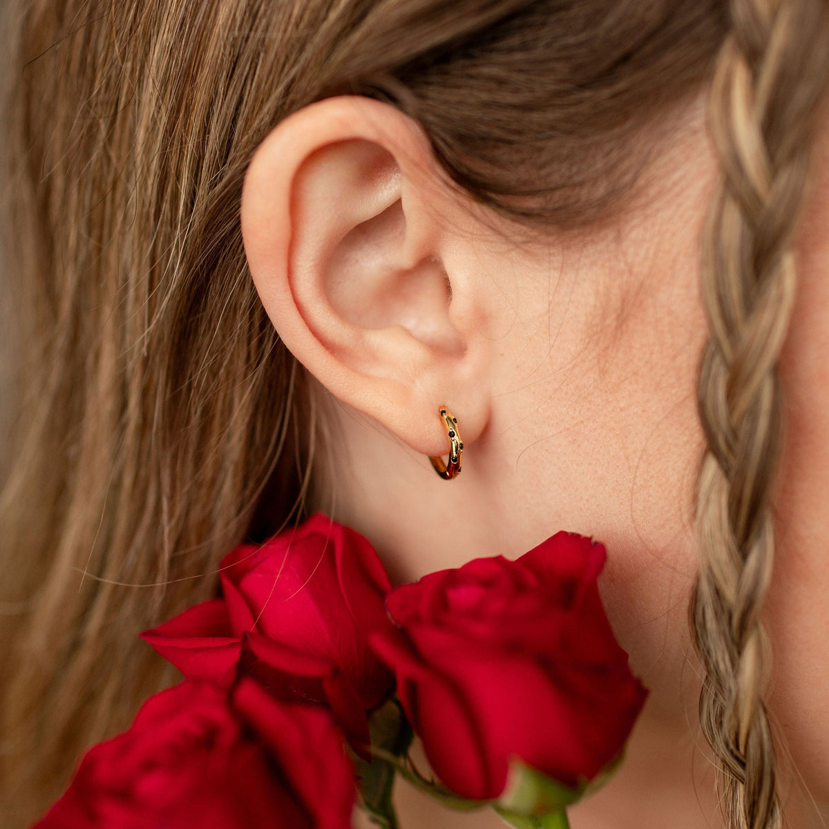 Girl wearing gold hoop earring holding red roses