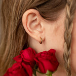 Girl wearing gold hoop earring holding red roses