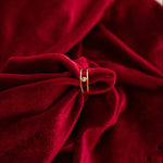 Close-up of a red velvet fabric with a gold ring