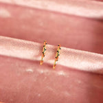 Gold hoop earrings on a pink velvet surface
