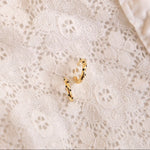 Gold hoop earrings on a textured beige fabric background