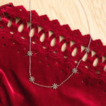 Load image into Gallery viewer, Silver necklace with floral pendants on a red lace garment against a wooden background

