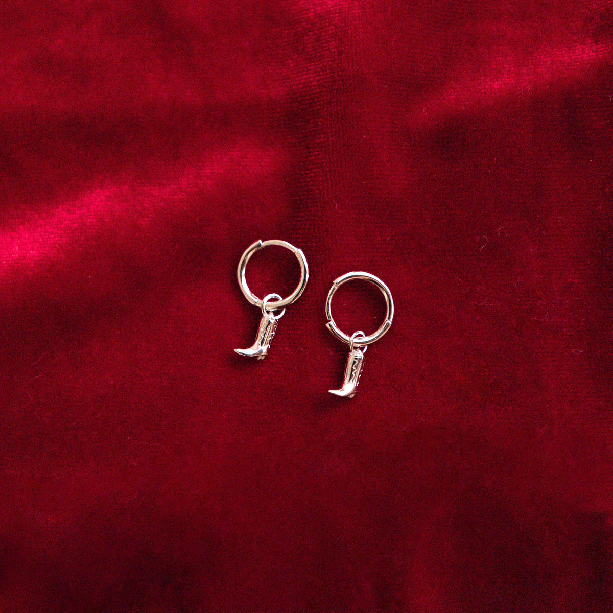 Silver hoop earrings on a red textured fabric background