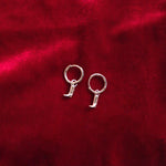 Silver hoop earrings on a red textured fabric background