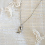 Silver necklace with a boot pendant on a textured white background