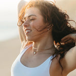 Woman with wavy hair smiling outdoors with a blurred background