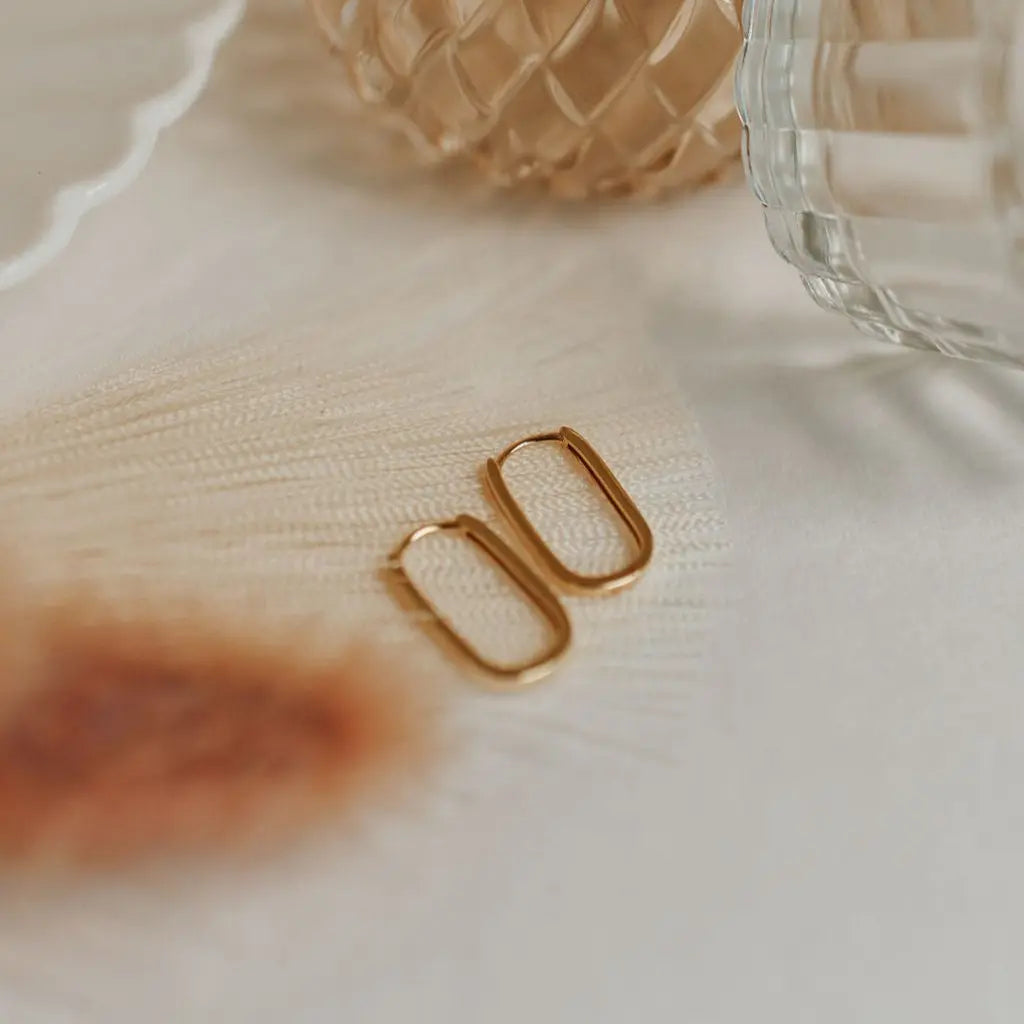 Gold hoop earrings on a textured surface with a blurred background