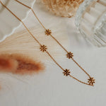 Gold necklace with floral pendants on a textured surface