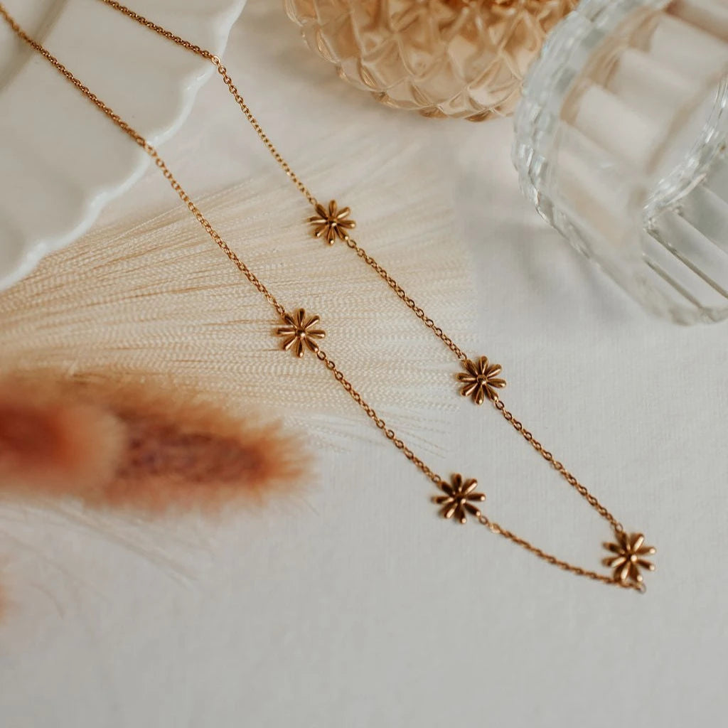 Gold necklace with floral pendants on a textured surface