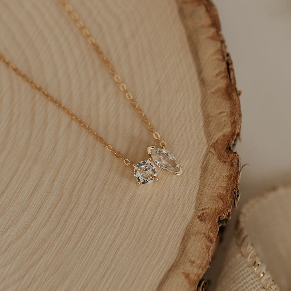 Gold necklace with a small diamond pendant on a wooden surface