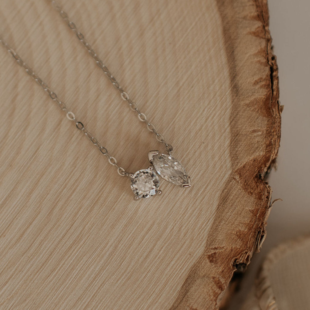 Silver necklace with a heart-shaped pendant on a wooden surface