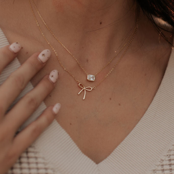 Necklace with a bow and gemstone pendant worn by a person