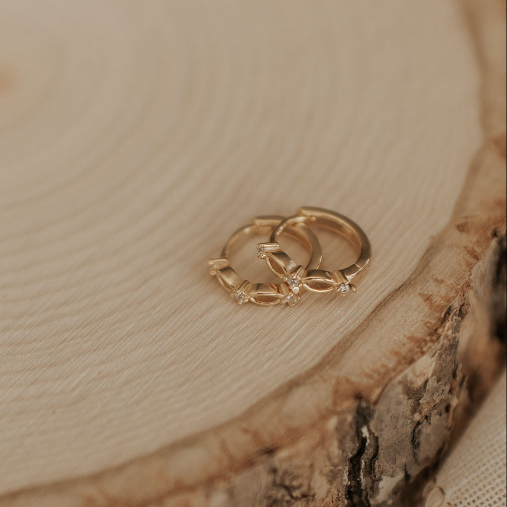 Gold earrings on a wooden surface