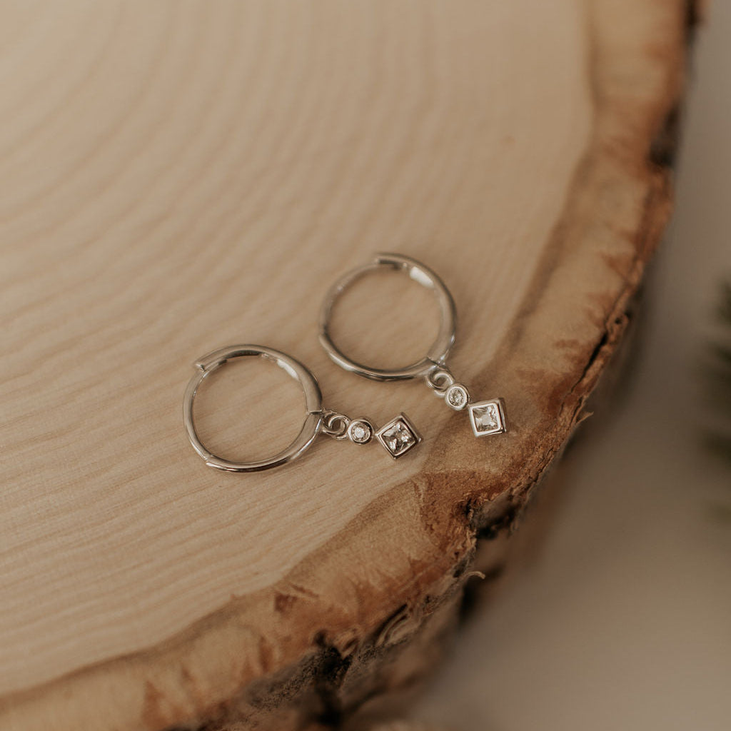Silver earrings with small diamonds on a wooden surface