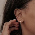 Load image into Gallery viewer, Close-up of a person adjusting an earring with a neutral background
