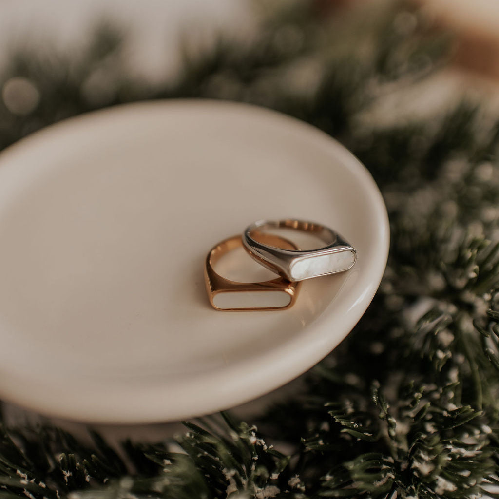 Two gold rings on a white dish with a blurred background