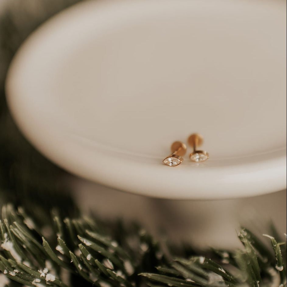 Pair of earrings on a white pedestal with a blurred green background