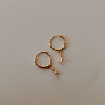 Load image into Gallery viewer, Gold hoop earrings with small diamond-shaped charms on a light gray background
