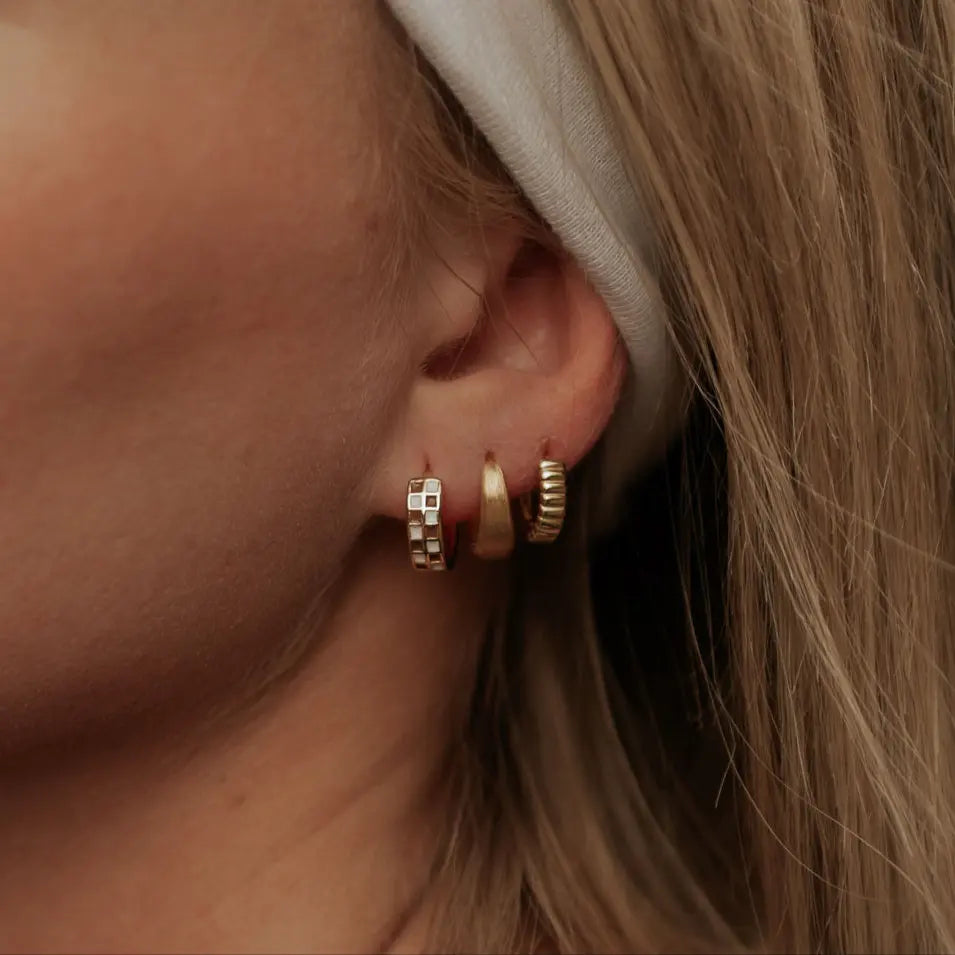Close-up of a person's ear wearing gold hoop earrings.