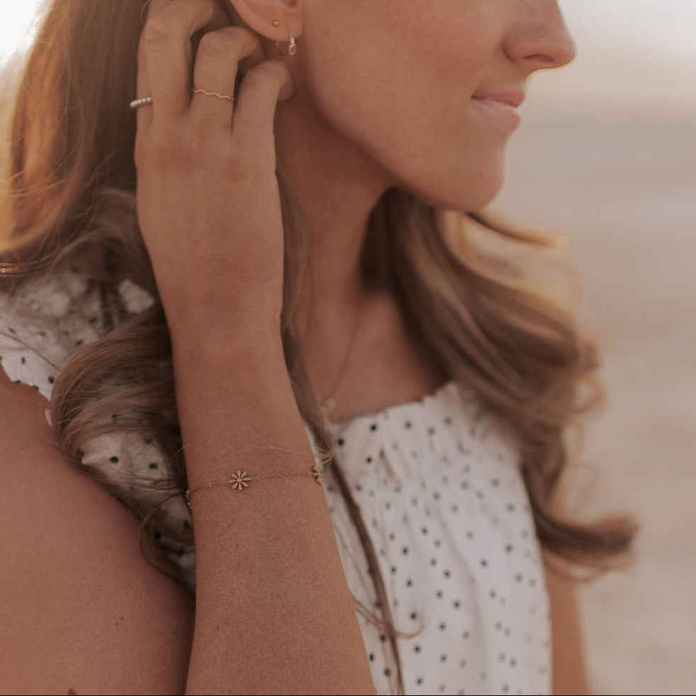 Woman adjusting an earring on a blurred beach background