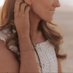 Load image into Gallery viewer, Woman adjusting an earring on a blurred beach background
