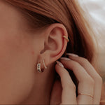Load image into Gallery viewer, Close-up of a person wearing a gold earring with a blurred background
