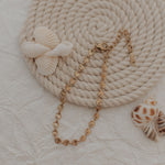 Load image into Gallery viewer, Gold bracelet with seashells on a textured beige surface
