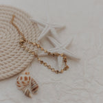 Load image into Gallery viewer, bracelet with a shell pendant on a textured surface
