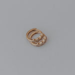 Gold star earrings with a small stone on a gray background