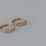Load image into Gallery viewer, Pair of gold hoop star earrings with small diamonds on a light gray background
