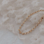 Load image into Gallery viewer, Gold bracelet on a textured white fabric background
